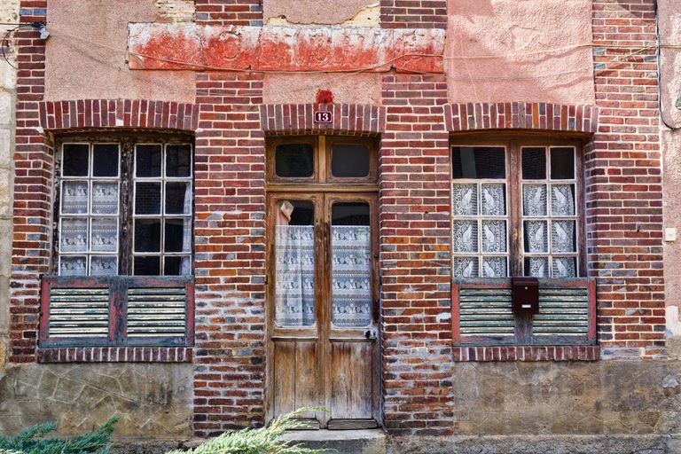 A rustic brick facade with wooden door and windows in Grandchamp, IDF, France.